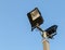Security floodlights on a tall post against a winter blue sky at