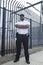 Security Guard Standing In Front Of Prison Fence