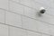 Security IR camera for city safety monitoring on gray stone tile on wall, diagonal view