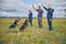 Security officers training detection dogs in grassy field