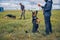 Security officers training detection dogs in grassy field