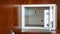 Security open metal safe with empty space inside in a wooden shelf. White safe box open door. Safe box with electronic lock in the