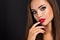 Seductive woman with dark brown eye makeup and bright red lips and nails