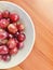 Seedless red grapes in white bowl, wooden background. Close up view.