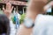 Seen between the hands of a boy high school student with a school bag waving as he greets his friend