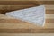 Segment of brie cheese on wood cutting board