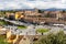 Segovia cityscape with road, green roundabout, cars passing and narrow stone streets, medieval architectur.