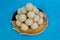 Seklective focus image of a pile of delicious Indian sweet Rava , semolina laddus in a plate with clear blue background