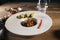 Select focus of a beautifully decorated plate of beef stew with out of focus food on a wooden table