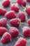 Selected raspberries arranged on stone table, vertical food background