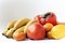 A selection of arranged different fresh fruits of bananas, mandarins, persimmons and lemons on white background close up