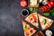 Selection of Assorted pieces pizza on black background and ingredients. Pepperoni, Vegetarian and Seafood Pizza