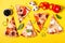 Selection of Assorted pieces pizza on yellow background and ingredients. Pepperoni, Vegetarian and Seafood Pizza