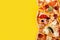Selection of Assorted pieces pizza on yellow background. Pepperoni, Vegetarian and Seafood Pizza
