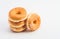 Selection of freshly-baked doughnuts with glazed icing, arranged in a tower on a white background