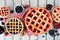 Selection of homemade fruit pies. Above view table scene over rustic white wood.