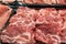 Selection of quality meat at a butcher shop, butchered pork in a refrigerated display case under glass, close up