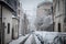 Selective blur on a Typical street of belgrade city center, stari grad, during a snowstorm, with blurry snow falling cars covered