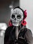 Selective color, black and red, portrait of woman wearing a sugar skull mask for dia de los muertos / day of the dead celebrated