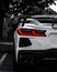 Selective color vertical of the back of a white Chevrolet Corvette C8 sportscar in a parking lot