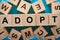 Selective focus of adopt word made of wooden cubes.