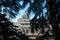 Selective focus of the Almudena Cathedral surrounded by trees under a blue sky in Madrid, Sp