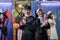 Selective focus on Asian young man and woman dressed as nun and priest smiling and holding drink at Halloween party with friends