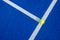 Selective focus of a ball on the white line of a blue paddle tennis court