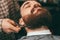 Selective focus of barber making beard haircut with scissors