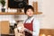 Selective focus of beautiful barista wiping cup while standing near espresso machine in cafe.