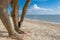 Selective focus on beautiful female foot with bright red pedicure on the beach sand. Hands smear healing mud on the