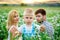 Selective focus. A blond son with a sad, hurt face in the foreground, a mother and father in the background on a blooming field of