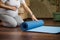 Selective focus on a blue exercise mat on a wooden floor, and a pregnant woman ready for pregnancy yoga practice indoors