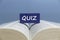 Selective focus of blue wooden block written with Quiz on an open book
