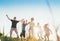 Selective focus brothers and sisters teenagers and little kids jumping holding hands in hands on the green grass meadow with an