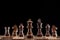 Selective focus of brown wooden queen on chessboard isolated on black.