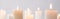 Selective focus of burning white candles glowing isolated on grey, panoramic shot