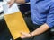 Selective focus businessman put confidential documents into brown envelope in office
