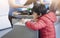 Selective focus of Child boy standing next to counter looking at the hole on charity box with blurry women standing behind, School