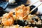 Selective focus of chopsticks holding california roll maki sushi with crispy fried dough topped with mayonnaise