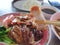 Selective focus of chopsticks holding fried pork crackling slice in restaurant