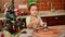 Selective focus on Christmas tree on a table against a blurred child girl enjoys playing with gingerbread cookie cutters