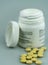 Selective focus close up of white prescription pill bottle and yellow pills