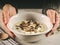 Selective focus closeup of a female\'s hands holding a bowl of mushroom soup