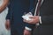 Selective focus closeup of a male\'s hands holding wedding rings on a ring cushion