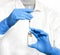 Selective focus closeup of a pair of hands wearing gloves while holding a syringe and a vaccine