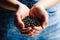 Selective focus closeup shot of coffee beans scooped inside cupped hands of a person