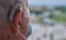 Selective focus closeup shot of an old male wearing hearing aids and a facemask