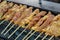 Selective focus closeup of some pork being grilled in a barbecue.Grilled pork satay is a popular Thai street food.