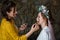 Selective focus. Creative work. A young female stylist makes up a beautiful bride with a hairstyle and a flower wreath. Morning of